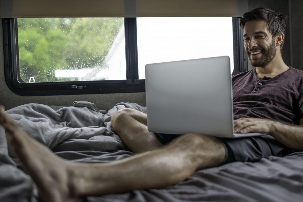 Mann arbeitet am Laptop im Wohnmobil