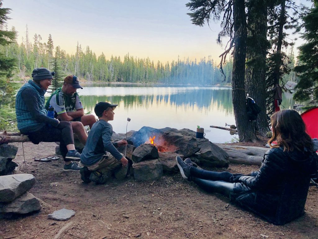 Familie am Lagerfeuer vor einem See